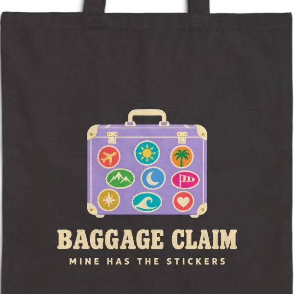 Close-up of the Baggage Claim design printed in warm cream ink on a black canvas tote, with the top seam and handles