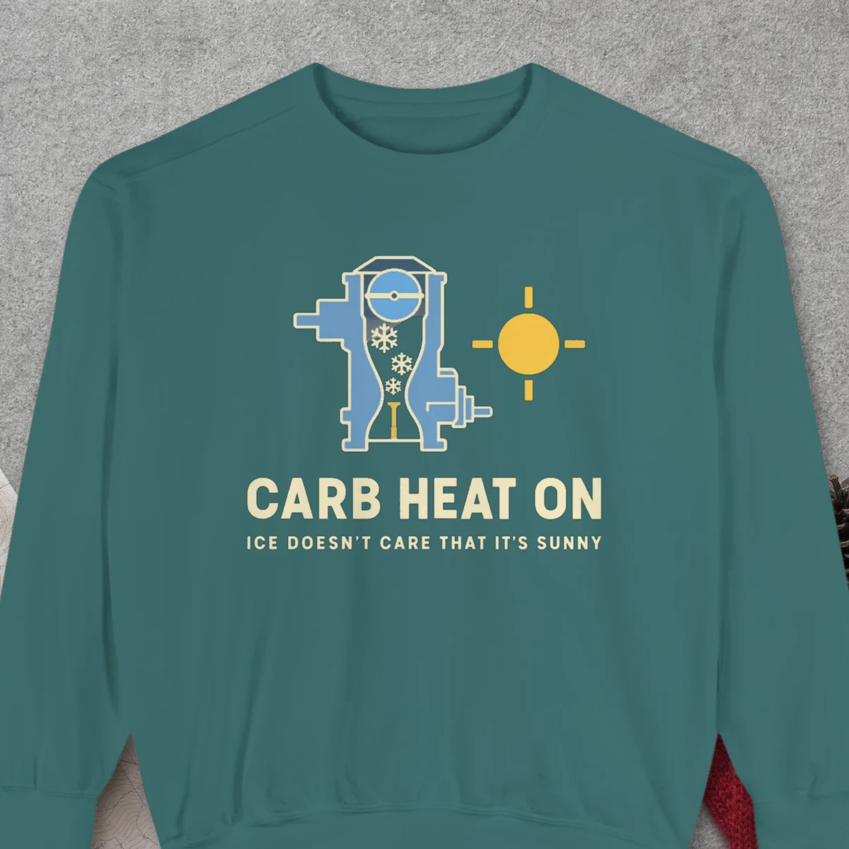 Carb Heat On design on a Blue Spruce Comfort Colors 1566 sweatshirt, laid flat on a winter ground