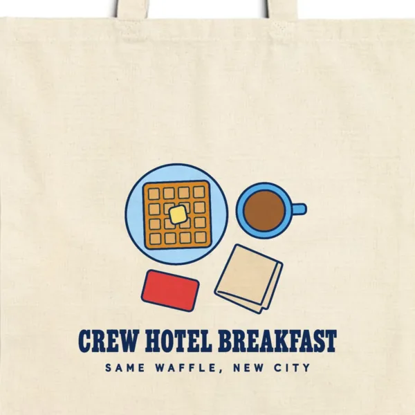 Close-up of the Crew Hotel Breakfast design printed in navy ink on a natural canvas tote, with the top seam and handles