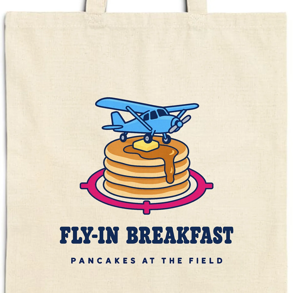 Close-up of the Fly-In Breakfast design printed in navy ink on a natural canvas tote, with the top seam and handles