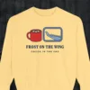 Frost on the Wing design on a Butter Comfort Colors 1566 sweatshirt, laid flat on a winter ground