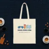 Her Cross-Country Kit design in navy ink on a natural canvas tote, laid flat on an airport lounge carpet