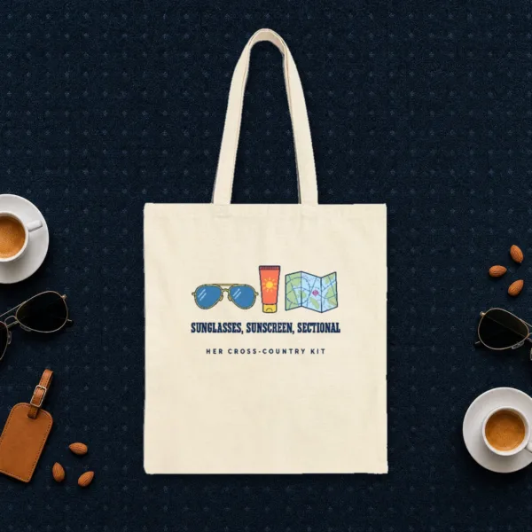 Her Cross-Country Kit design in navy ink on a natural canvas tote, laid flat on an airport lounge carpet