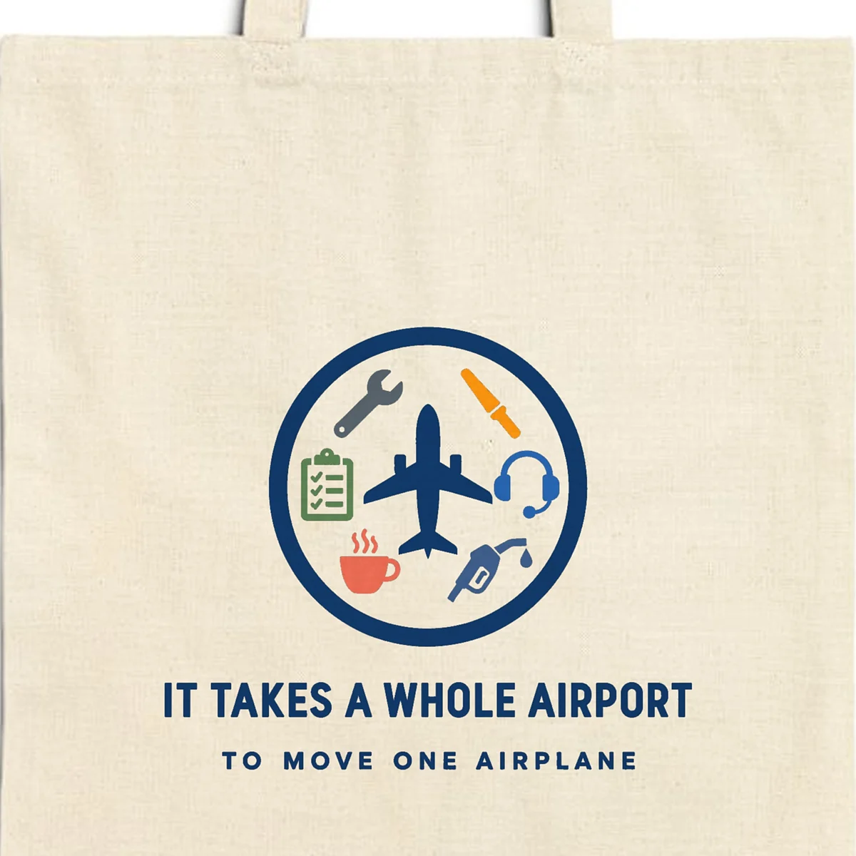 Close-up of the It Takes a Whole Airport design printed in navy ink on a natural canvas tote, with the top seam and handles