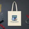 Never Fully Unpacked design in navy ink on a natural canvas tote, laid flat on a hangar floor