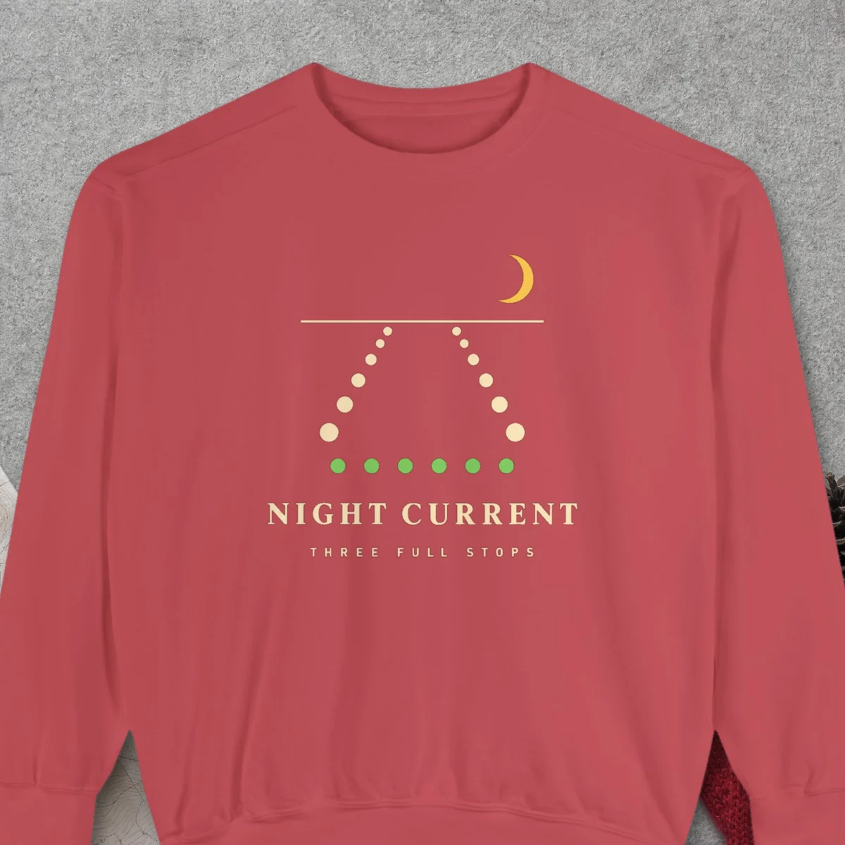 Night Current design on a Crimson Comfort Colors 1566 sweatshirt, laid flat on a winter ground