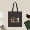 Packed by a Pilot design in warm cream ink on a black canvas tote, laid flat on a light terrazzo terminal floor