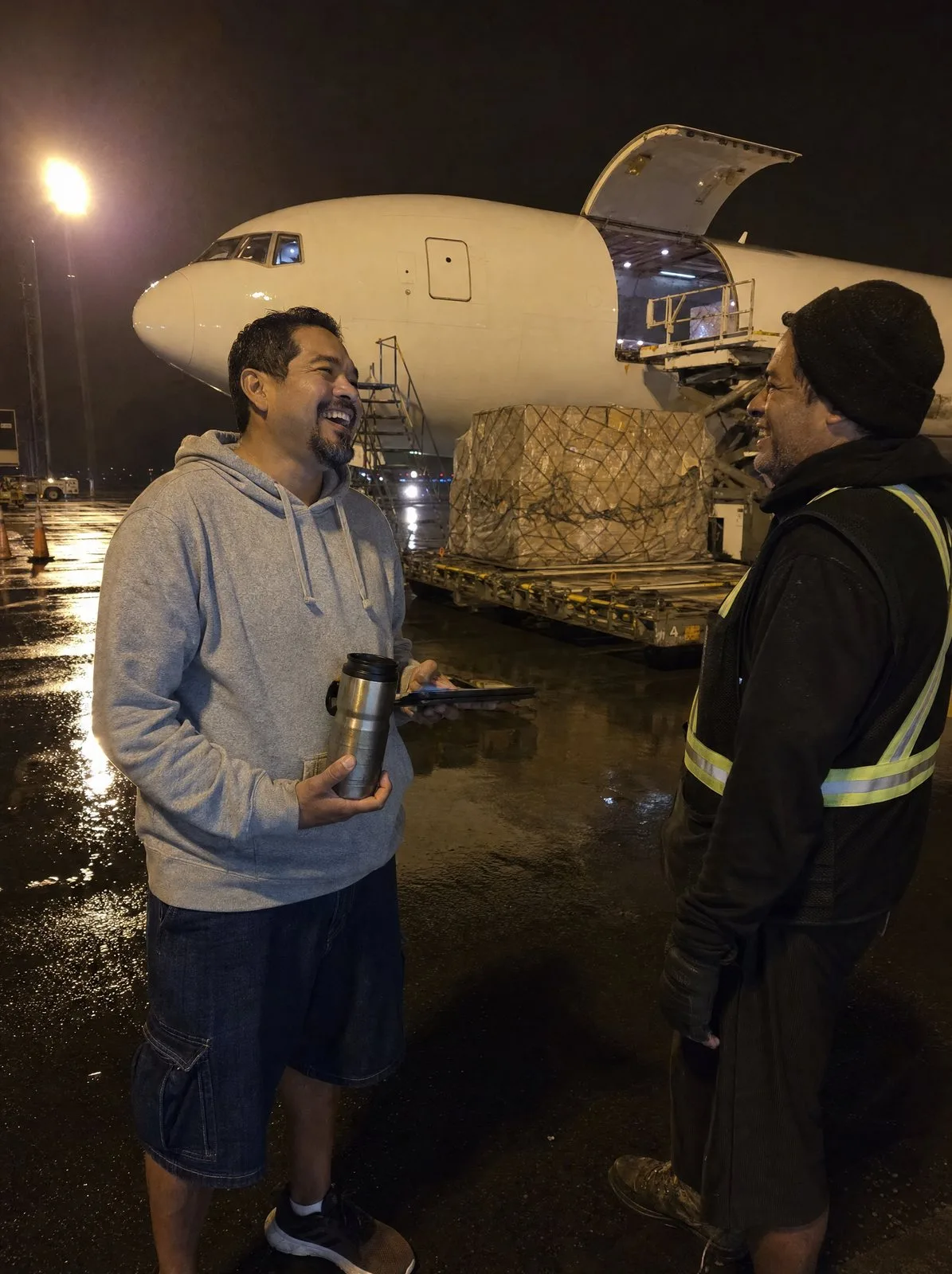 A cargo pilot laughs on a night apron beside a big freighter