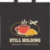 still-holding-tote-black-detail Close-up of the Still Holding design printed in warm cream ink on a black canvas tote, with the top seam and handles