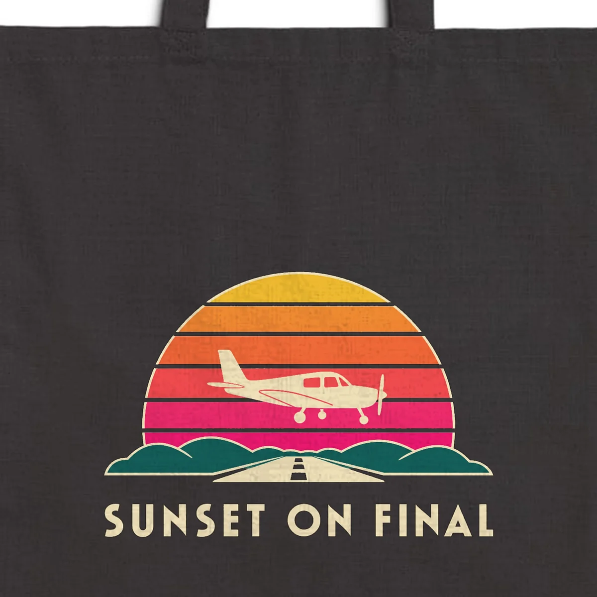 Close-up of the Sunset on Final design printed in warm cream ink on a black canvas tote, with the top seam and handles