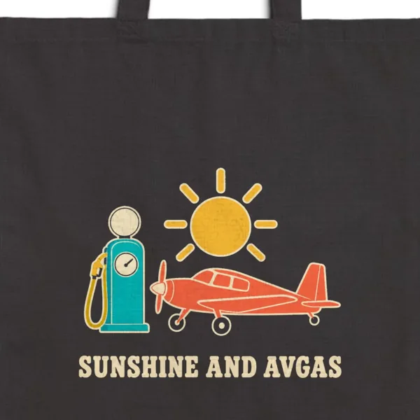sunshine-and-avgas-tote-black-detail Close-up of the Sunshine and Avgas design printed in warm cream ink on a black canvas tote, with the top seam and handles